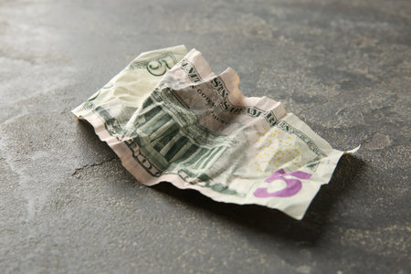 One crumpled dollar banknote on grey table, closeup
