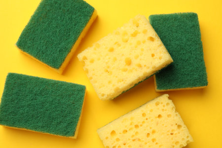 Soft sponges on yellow background, flat lay. Cleaning toolの写真素材