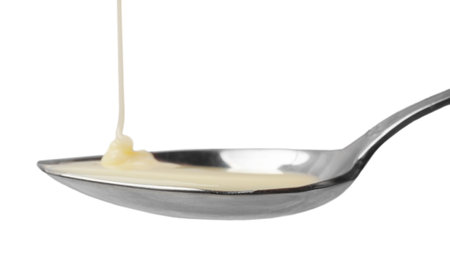 Delicious condensed milk pouring onto spoon isolated on whiteの写真素材