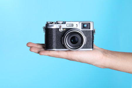 Photographer with vintage camera on light blue background, closeupの写真素材