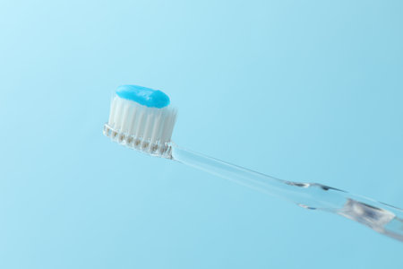 Toothbrush with toothpaste in air on light blue background, closeup