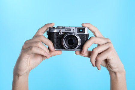 Photographer with vintage camera on light blue background, closeupの写真素材
