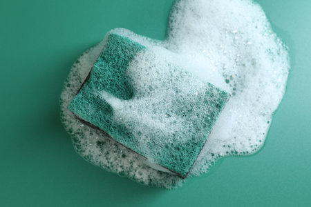 One sponge with foam on green background, top view