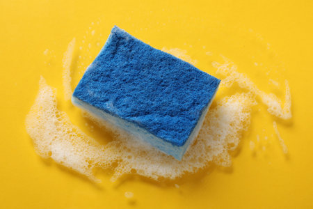 One cleaning sponge and foam on yellow background, above view