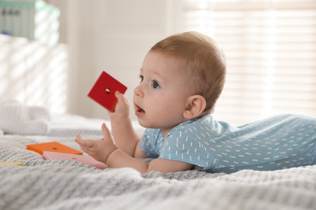 Cute little baby with toys on bed at home