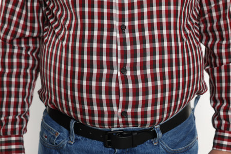 Overweight man in tight shirt on white background, closeup