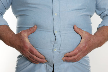 Overweight man in tight shirt on white background, closeupの写真素材