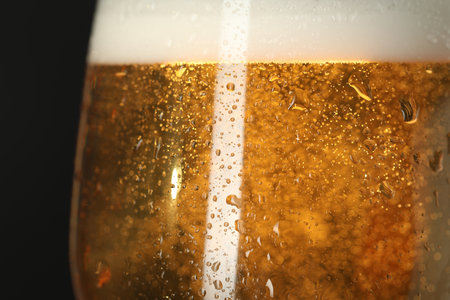 Glass of beer with condensation drops on black background, macro viewの写真素材