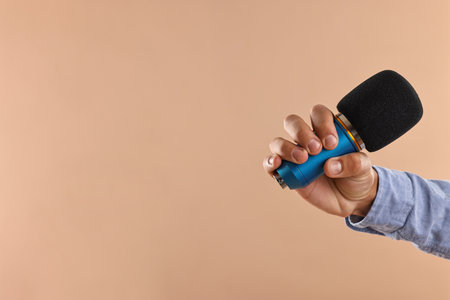 Man with microphone on beige background, closeup. Space for textの写真素材