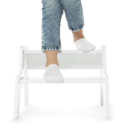 Little girl standing on step stool against white background, closeup