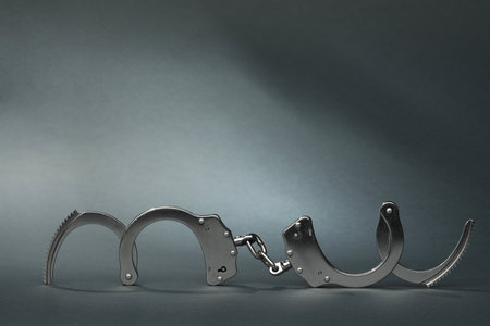 Metal chain handcuffs on gray background. Space for text