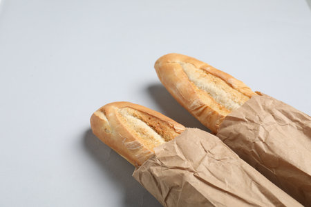 Paper bags with fresh baguettes on white background, above view. Space for textの写真素材