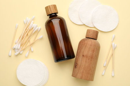 Cotton pads, bottles of cosmetic products and swabs on beige background, flat layの写真素材