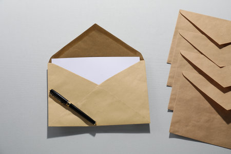 Kraft paper envelopes with letter and pen on gray background, flat lay. Mockup for designの写真素材