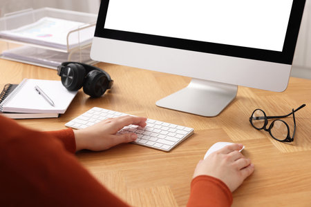 Woman working on computer at wooden table in office, closeupの写真素材