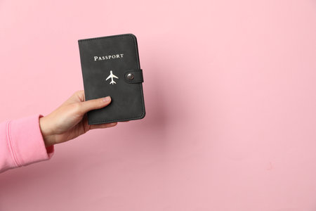 Woman holding passport on pink background, closeup. Space for textの写真素材