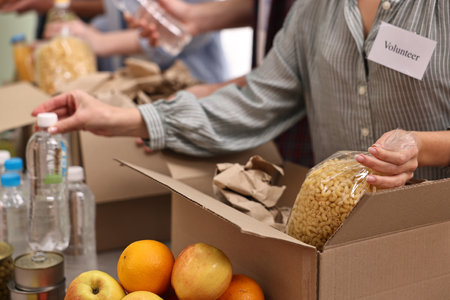 Volunteers packing food donations at table indoors, closeupの写真素材