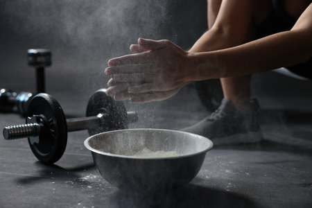 Woman clapping hands with powder above bowl before training in gym, closeupの写真素材