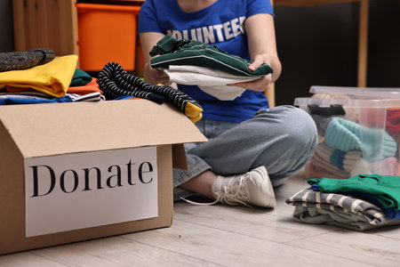 Volunteer putting clothes into donation box on floor indoors, closeupの写真素材