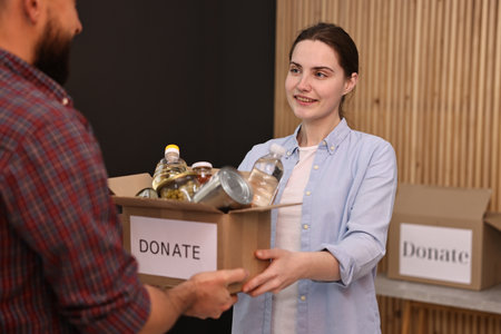 Volunteers holding donation box with food products indoors