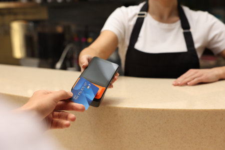 Man paying with credit card via terminal in cafe, closeup