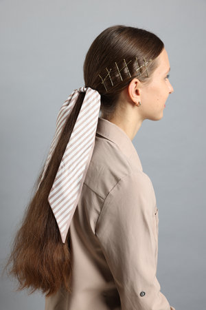 Teenage girl with stylish hair clips and bandana on light grey background