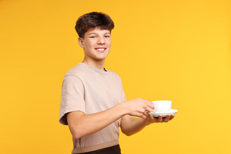 Teenage boy with cup on orange backgroundの写真素材