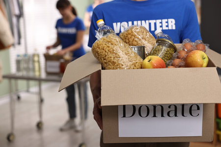 Volunteer holding donation box with food products indoors, closeupの写真素材