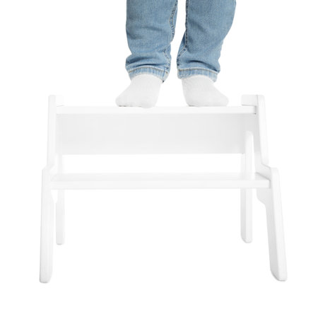 Little boy standing on step stool against white background, closeupの写真素材
