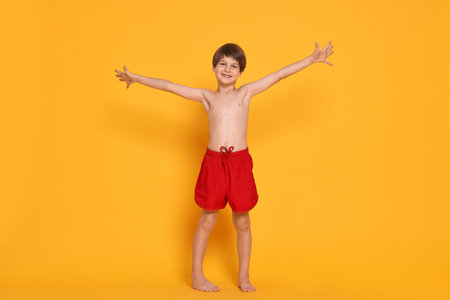 Happy little boy in swimwear on orange backgroundの写真素材