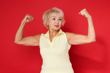 Senior woman exercising on red background. Healthy lifestyleの写真素材