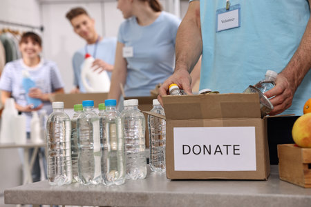 Group of volunteers packing donation goods indoors, closeup