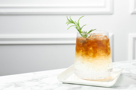 Refreshing espresso tonic drink with rosemary on white marble table, space for textの写真素材