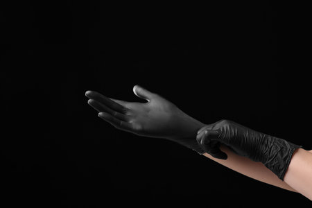 Person wearing latex gloves on black background, closeupの写真素材