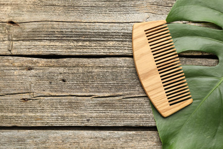 Comb and monstera leaf on wooden table, top view. Space for textの写真素材