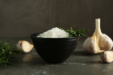 Sea salt in bowl, rosemary and garlic on gray table, closeupの写真素材