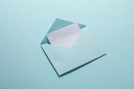 Paper envelope with letter on light blue background, above view. Mockup for designの写真素材