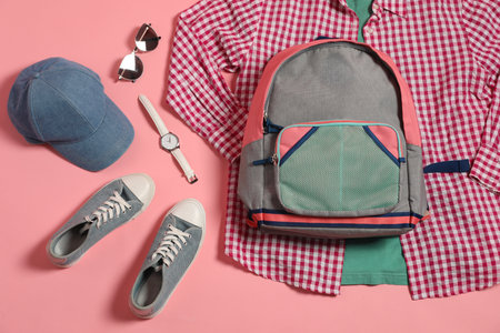 Stylish outfit with backpack on pink background, flat lay