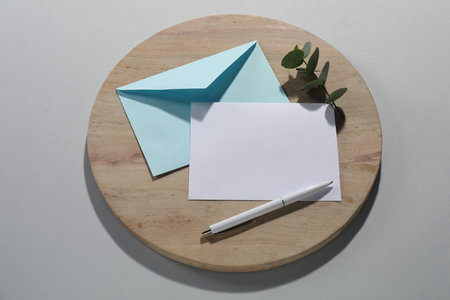 Paper envelope with letter, eucalyptus branch and pen on grey background, flat lay. Mockup for designの写真素材