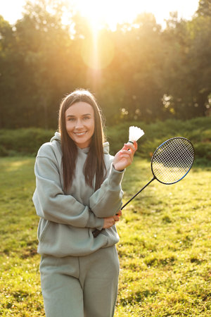 Happy young woman with badminton racket and shuttlecock in park on sunny dayの写真素材