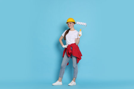 Young decorator with paint roller on light blue backgroundの写真素材
