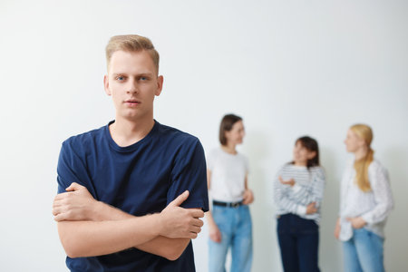 Young man feeling uncomfortable among people indoors, selective focusの写真素材