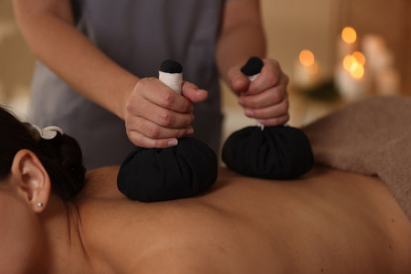 Woman receiving back massage with herbal bags in spa salon, closeupの写真素材