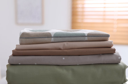 New clean folded bed linens on table indoors