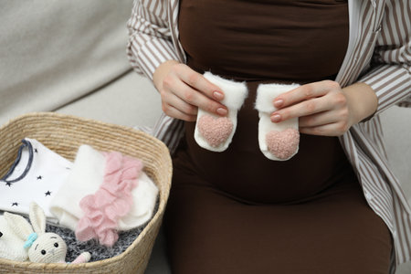 Pregnant woman with baby socks on sofa at home, closeupの写真素材