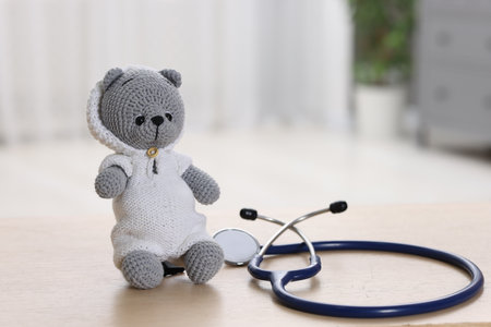 Pediatrics concept. Toy bear with stethoscope on table indoors, space for textの写真素材