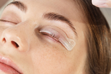 Eyelash lamination procedure. Woman with silicone pad on eyelid in beauty salon, closeupの写真素材