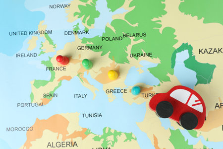 Red wooden toy car and human figures on world map, flat lay. Road trip planningの写真素材