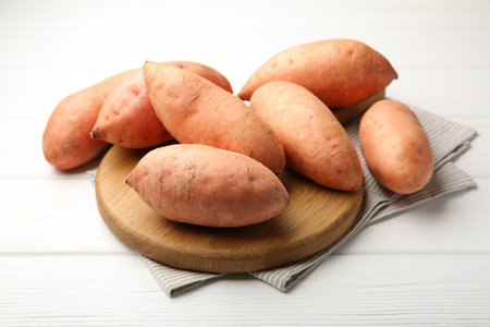 Fresh raw sweet potatoes on white wooden table, closeupの写真素材
