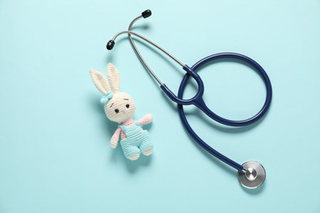 Pediatrics concept. Toy bunny with stethoscope on light blue background, top viewの写真素材